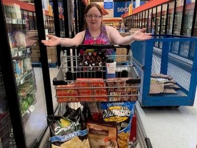 A picture of an adult at the grocery store with a full grocery cart.