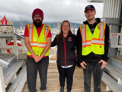 Three individuals standing on a dock smiling and posing for photo on first day of work.