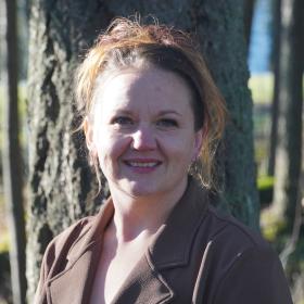 A smiling woman in a brown blazer